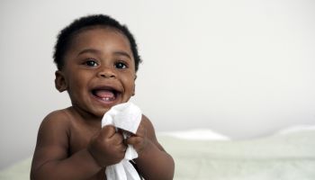 baby holding wipe smiling
