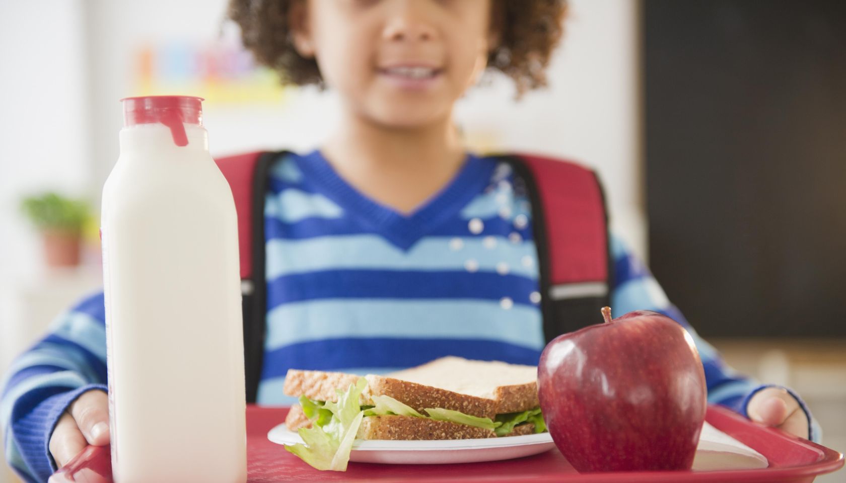 African American school girl holding lunch on a tray