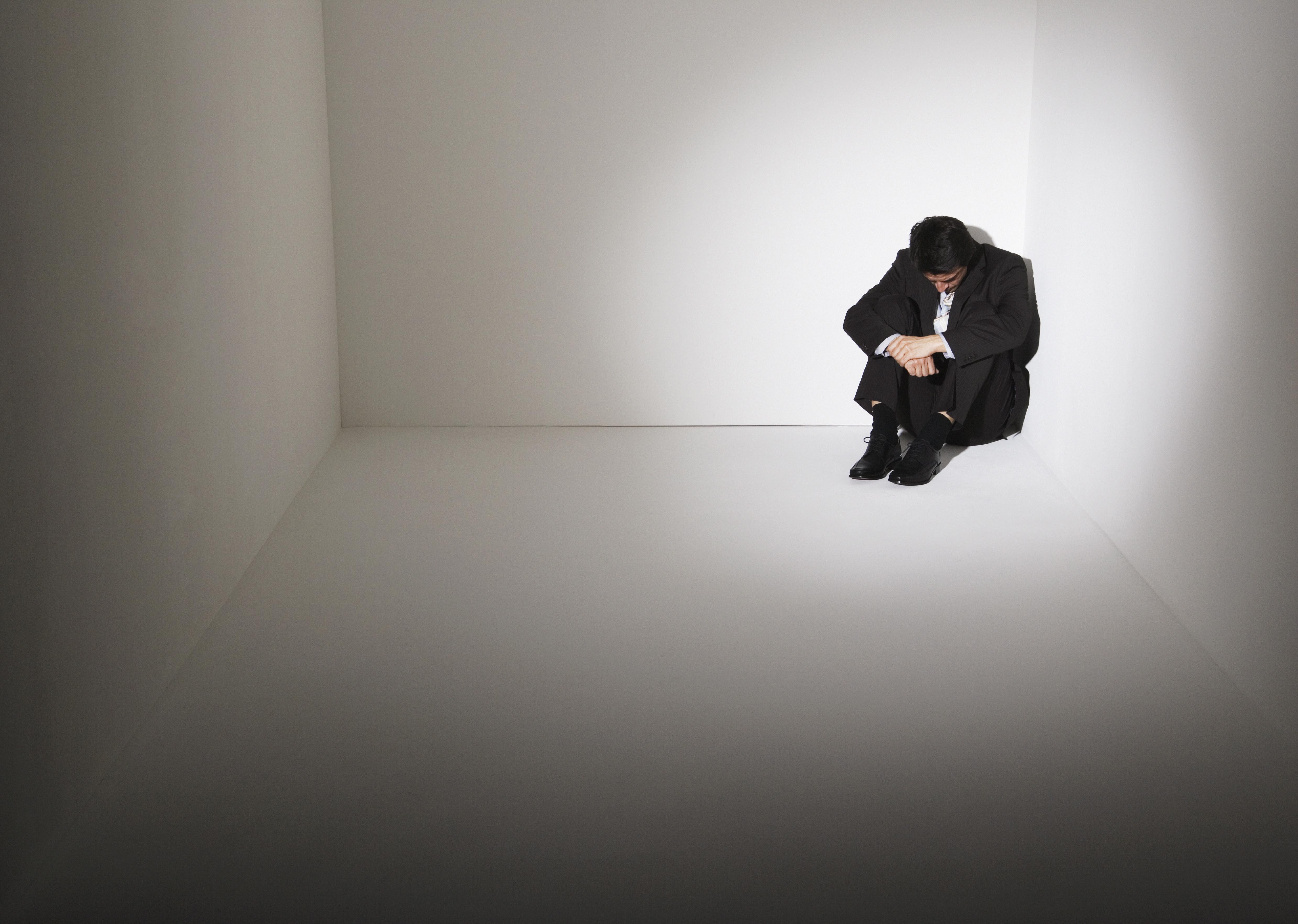 Businessman sitting on floor in corner of room