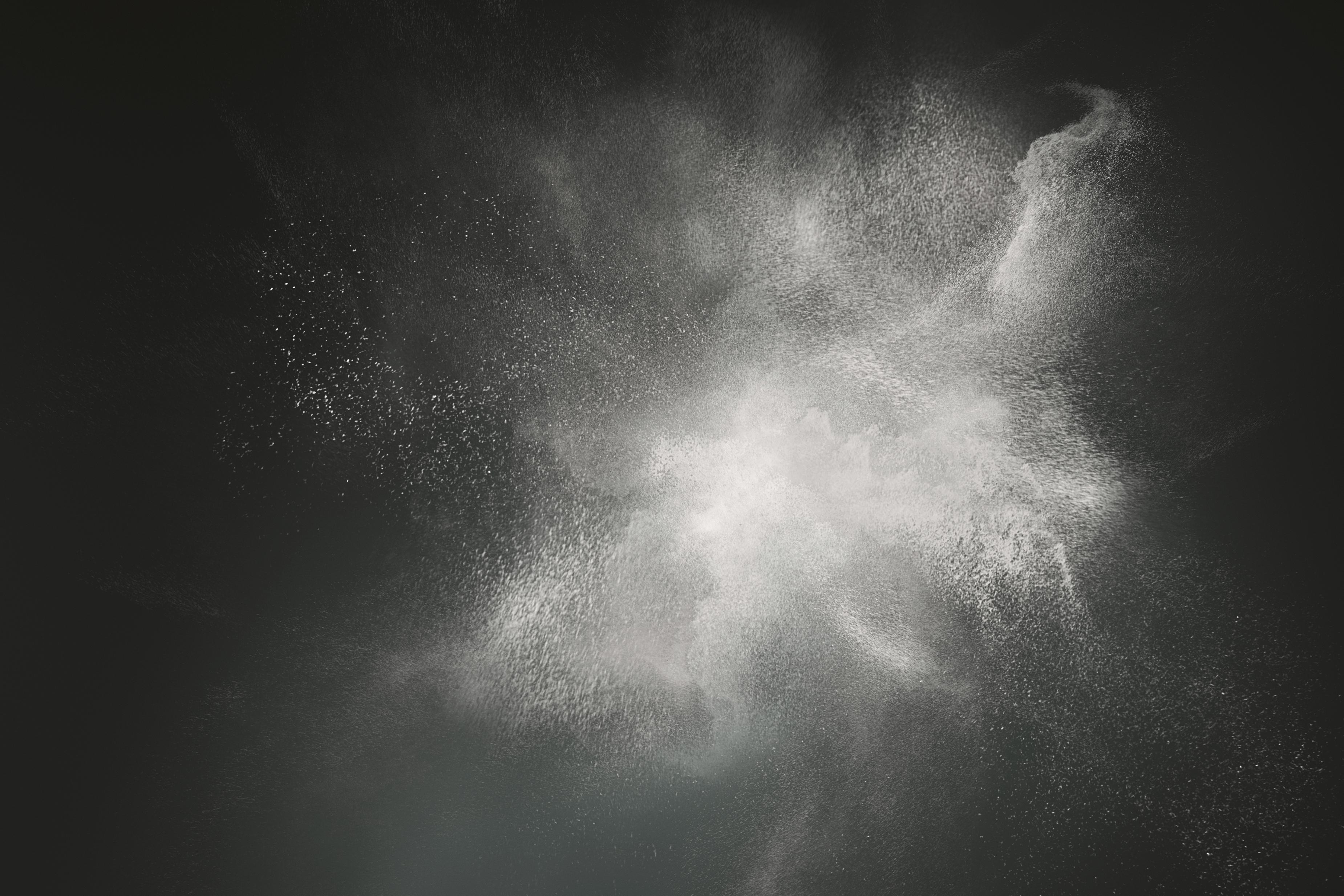 Abstract design of white powder cloud against dark background