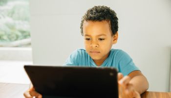 Mixed race boy using digital tablet at table