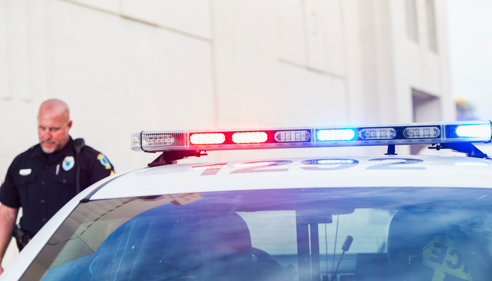 Officer walking back to police car with lights flashing