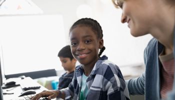 Portrait smiling pre-adolescent girl at computer in classroom