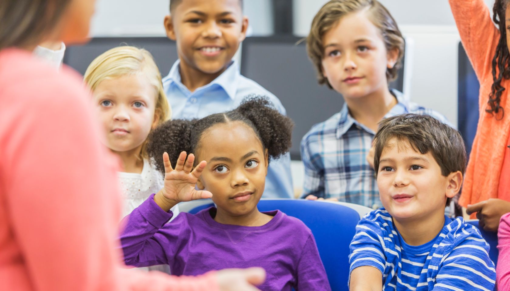 Multi-ethnic group of children, girl raising hand