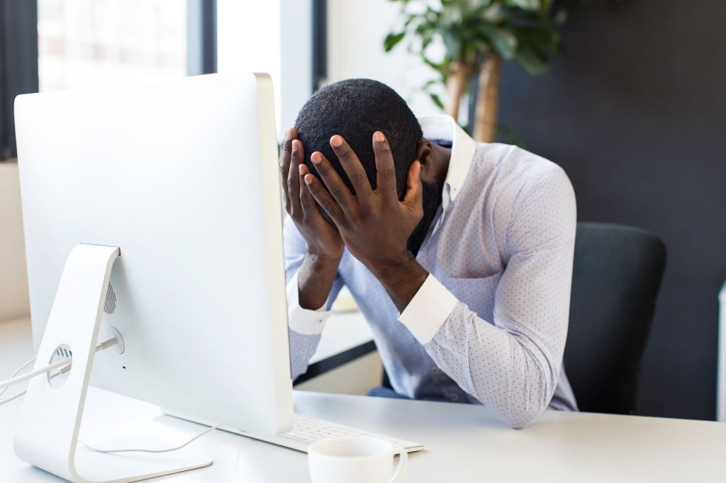 Stressed african businessman sitting at his desk.