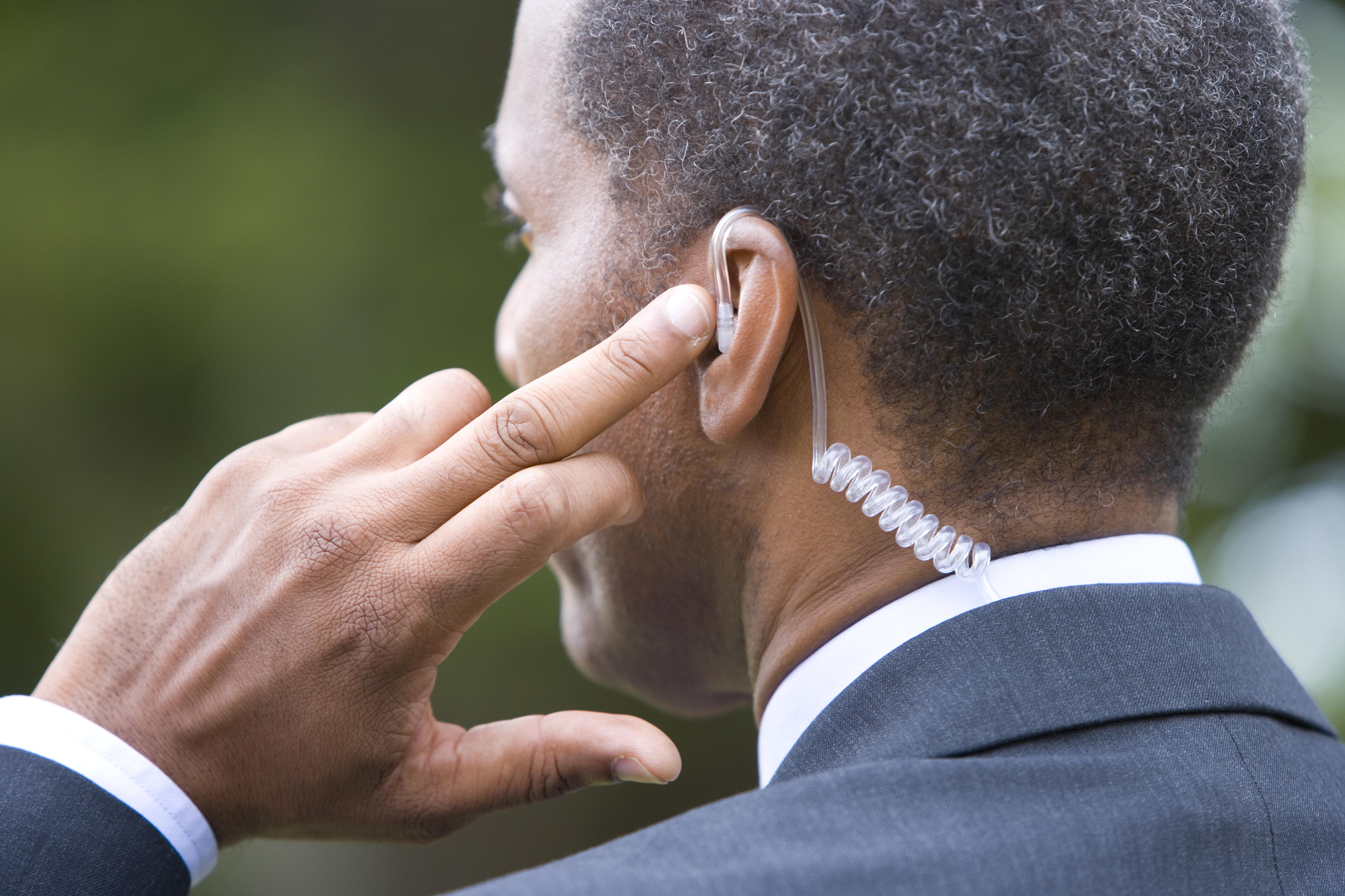 Man with finger on earpiece, rear view