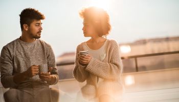 Young black couple talking to each other during coffee time.