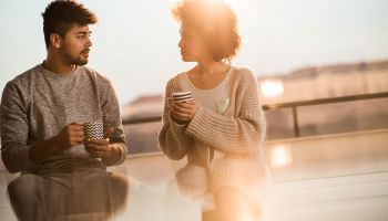 Young black couple talking to each other during coffee time.