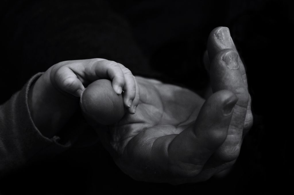 Cropped Hands Of Father And Baby Against Black Background