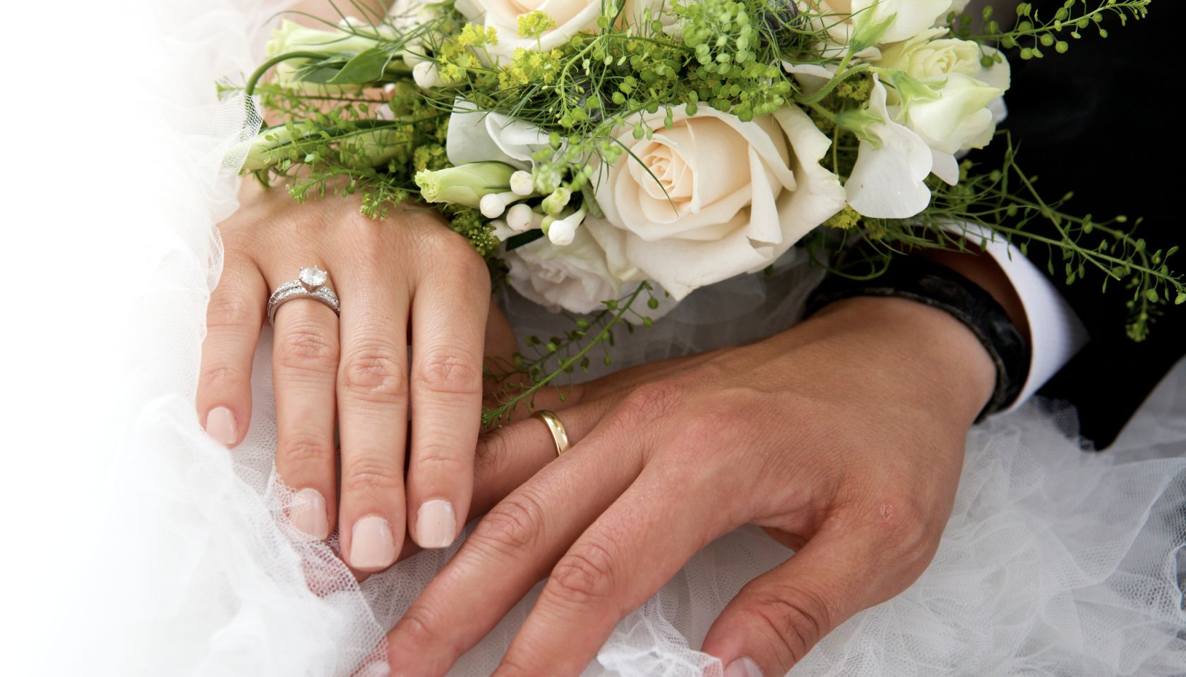 Close-Up Of Newlywed Couple Holding Rose Bouquet