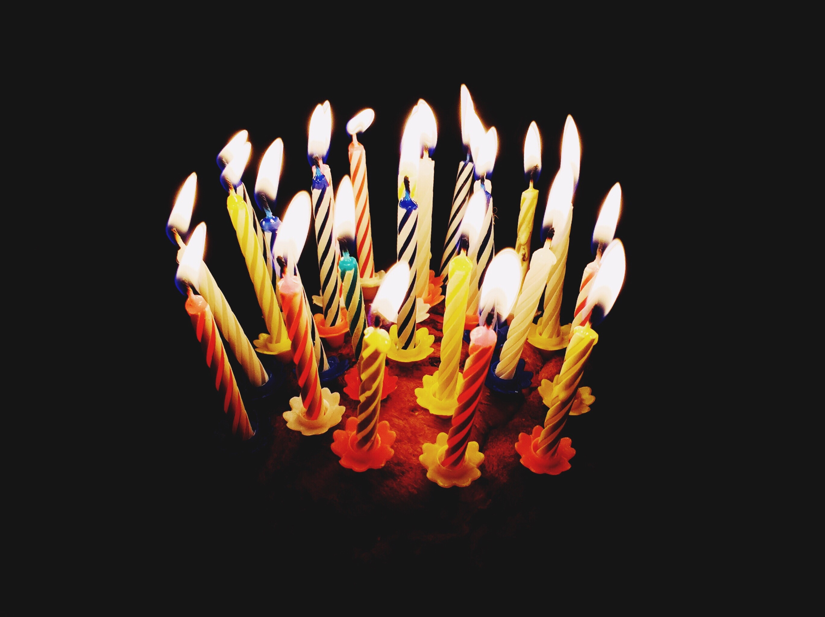 Close-Up Of Lit Candles Against Black Background