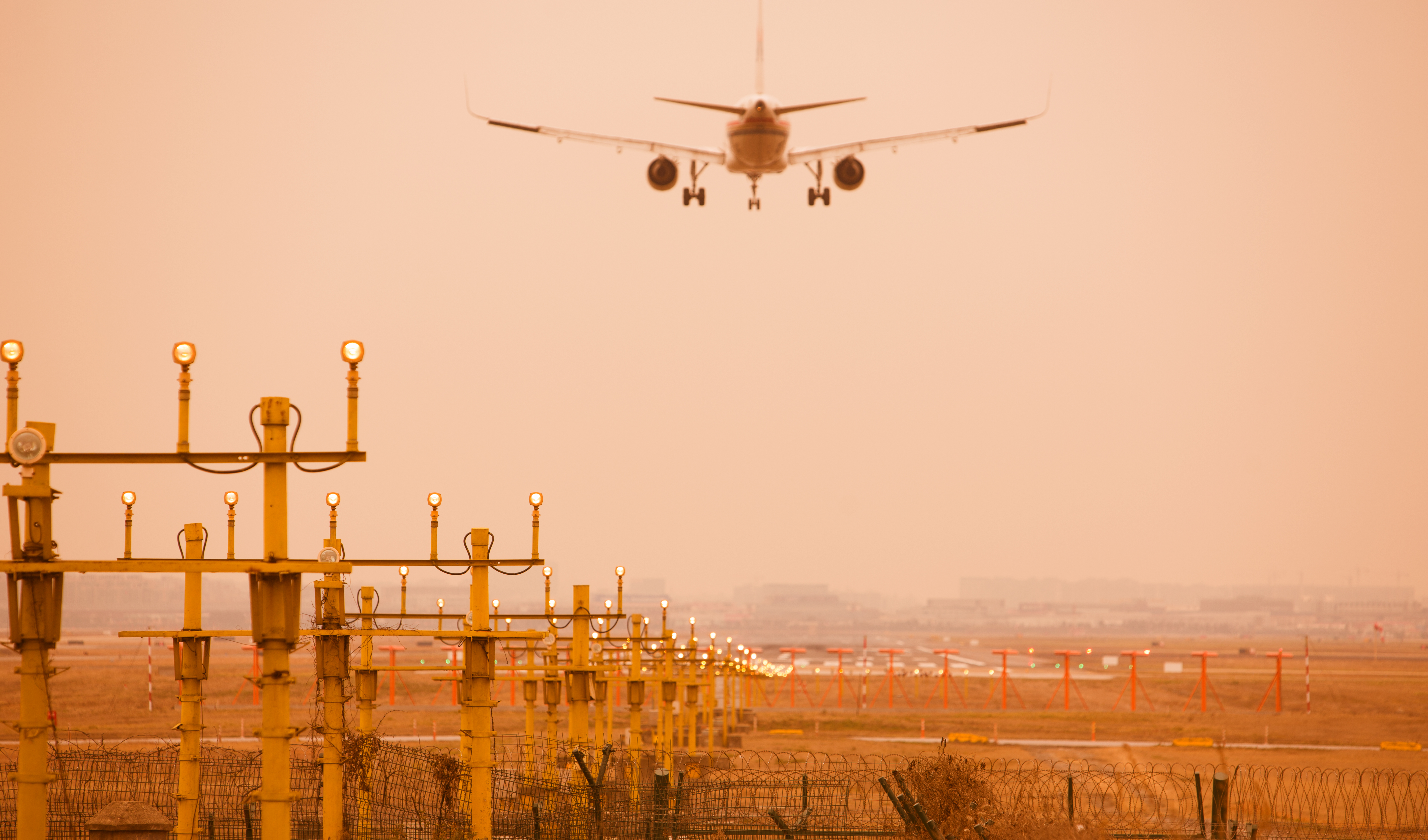Airplane landing at Shanghai Hongqiao Airport. Runway lights in the foreground.
