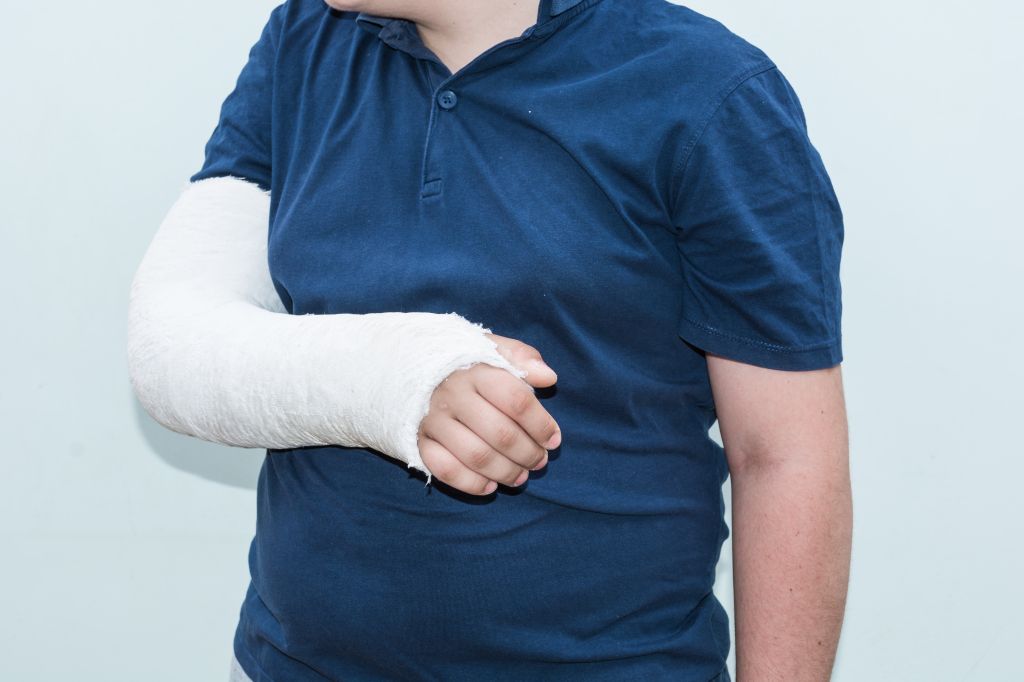 Midsection Of Teenage Boy With Injured Hand Against White Background