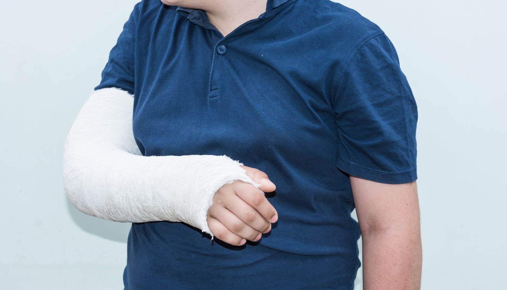 Midsection Of Teenage Boy With Injured Hand Against White Background