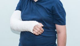 Midsection Of Teenage Boy With Injured Hand Against White Background