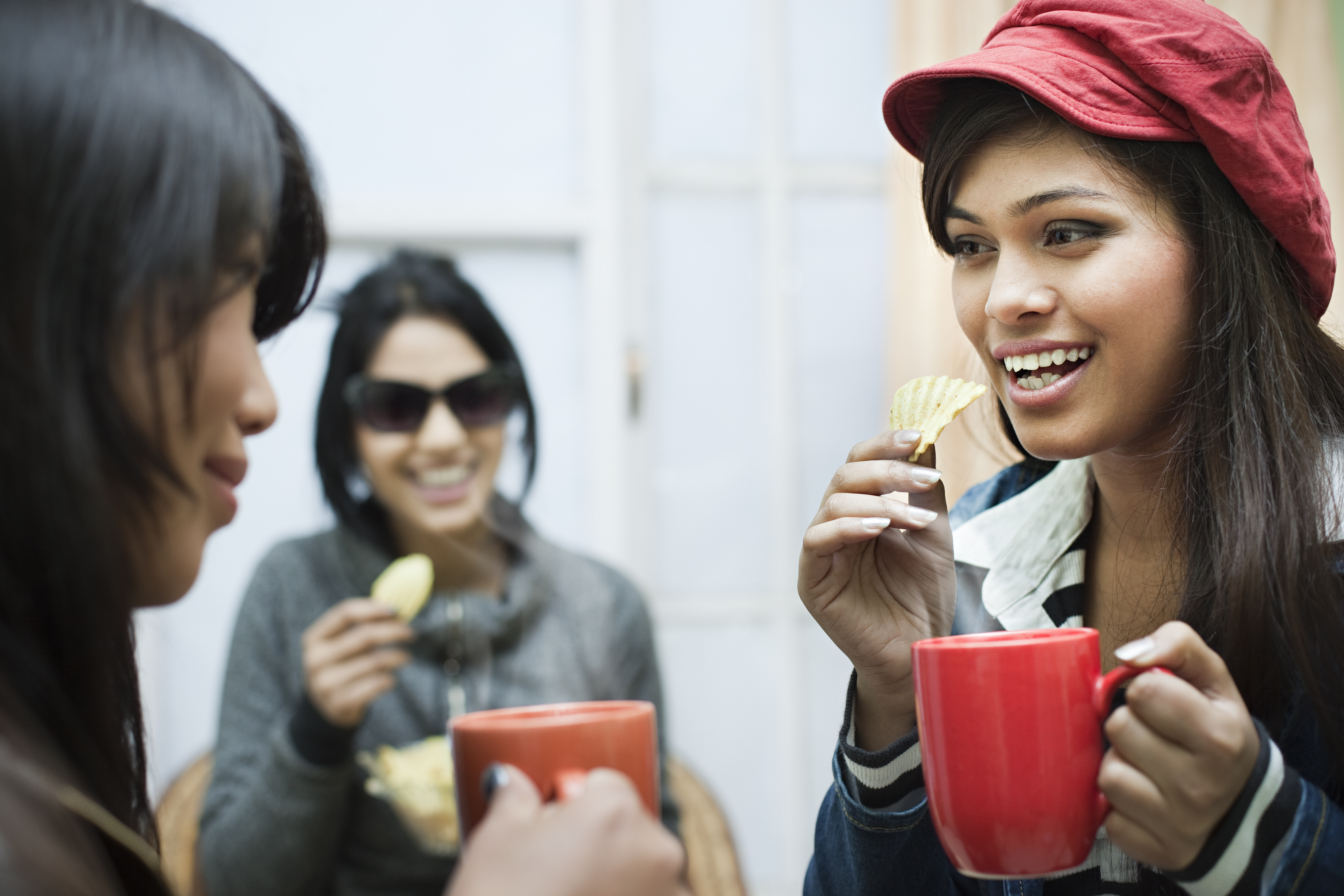 Happy multiracial group of female friends enjoying coffee with snacks.