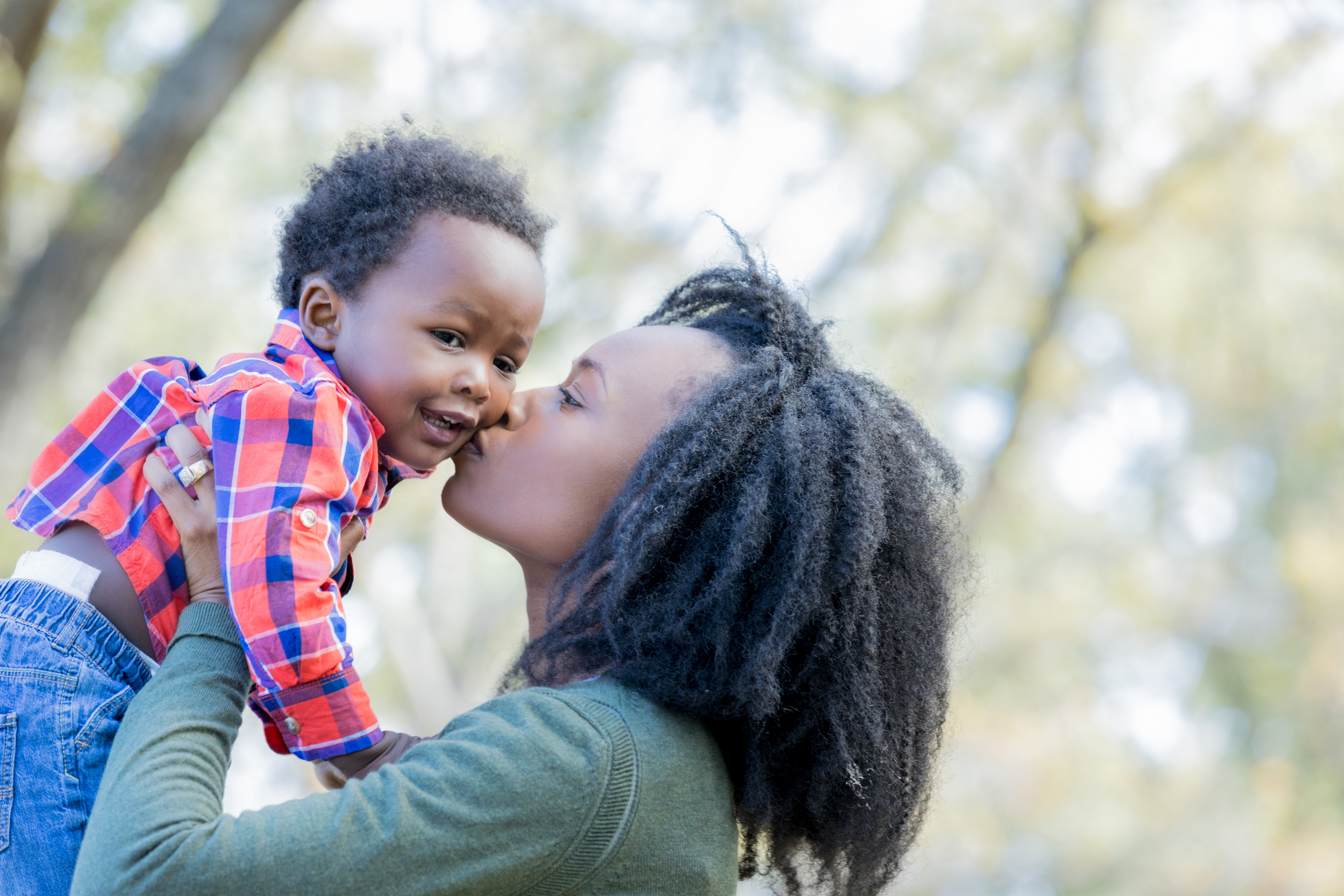 Loving mother kisses baby boy on cheek outside