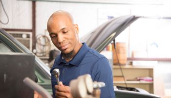 African descent mechanic working in auto repair shop.