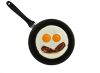 Fried eggs with bacon in pan, face with eyes