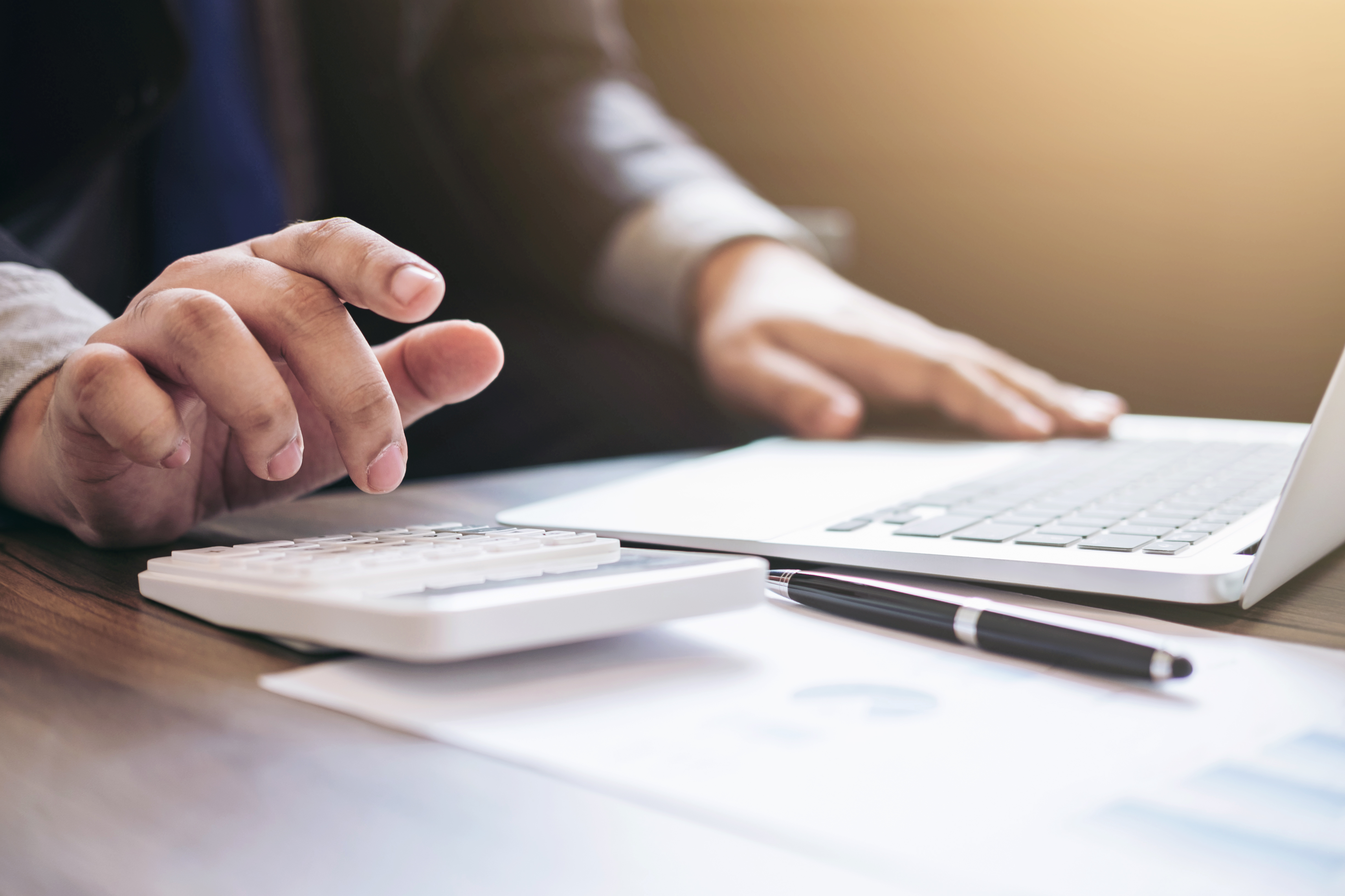 Midsection Of Man Using Calculator At Desk