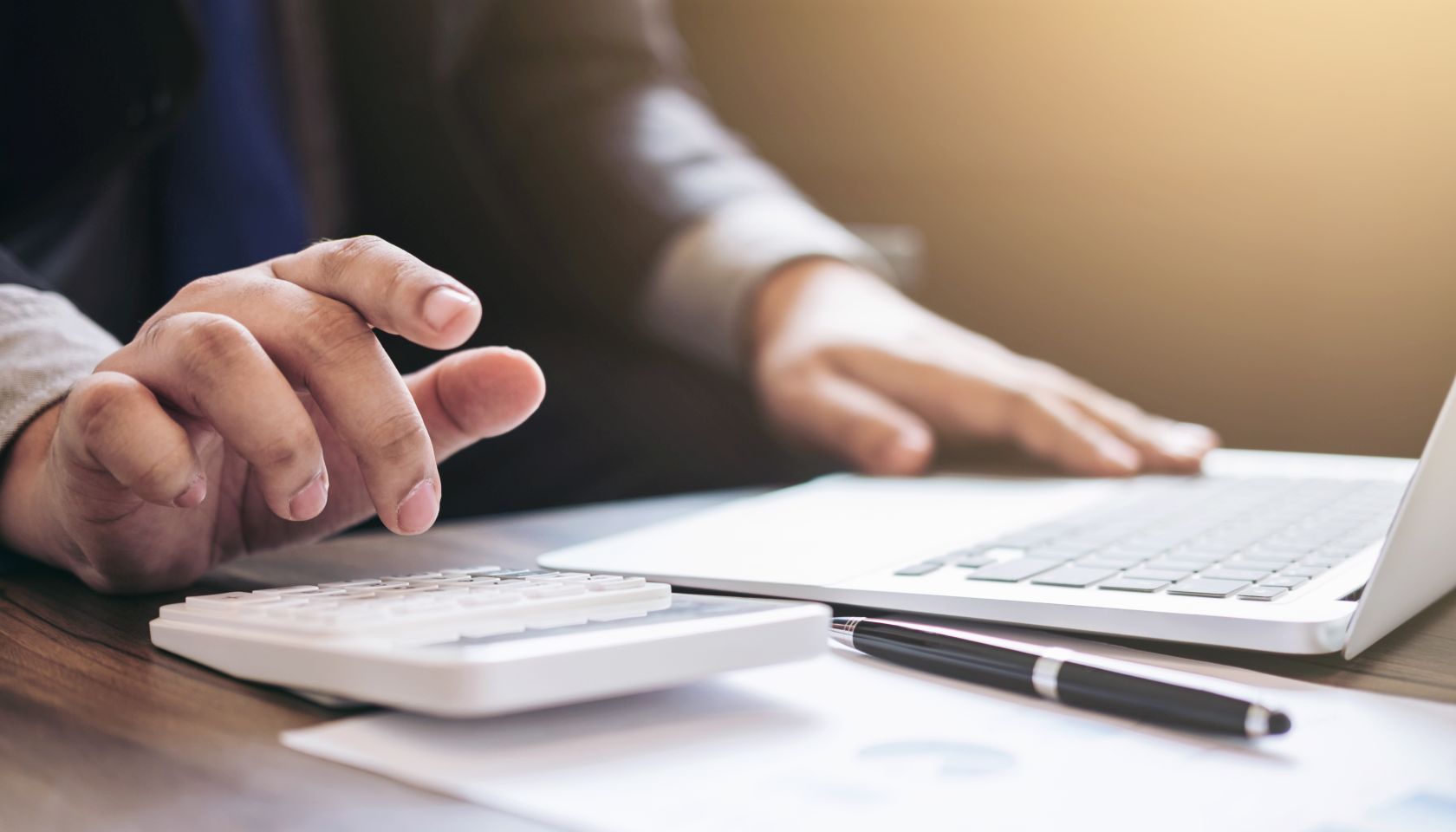 Midsection Of Man Using Calculator At Desk