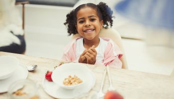 Portrait smiling girl eating breakfast at table