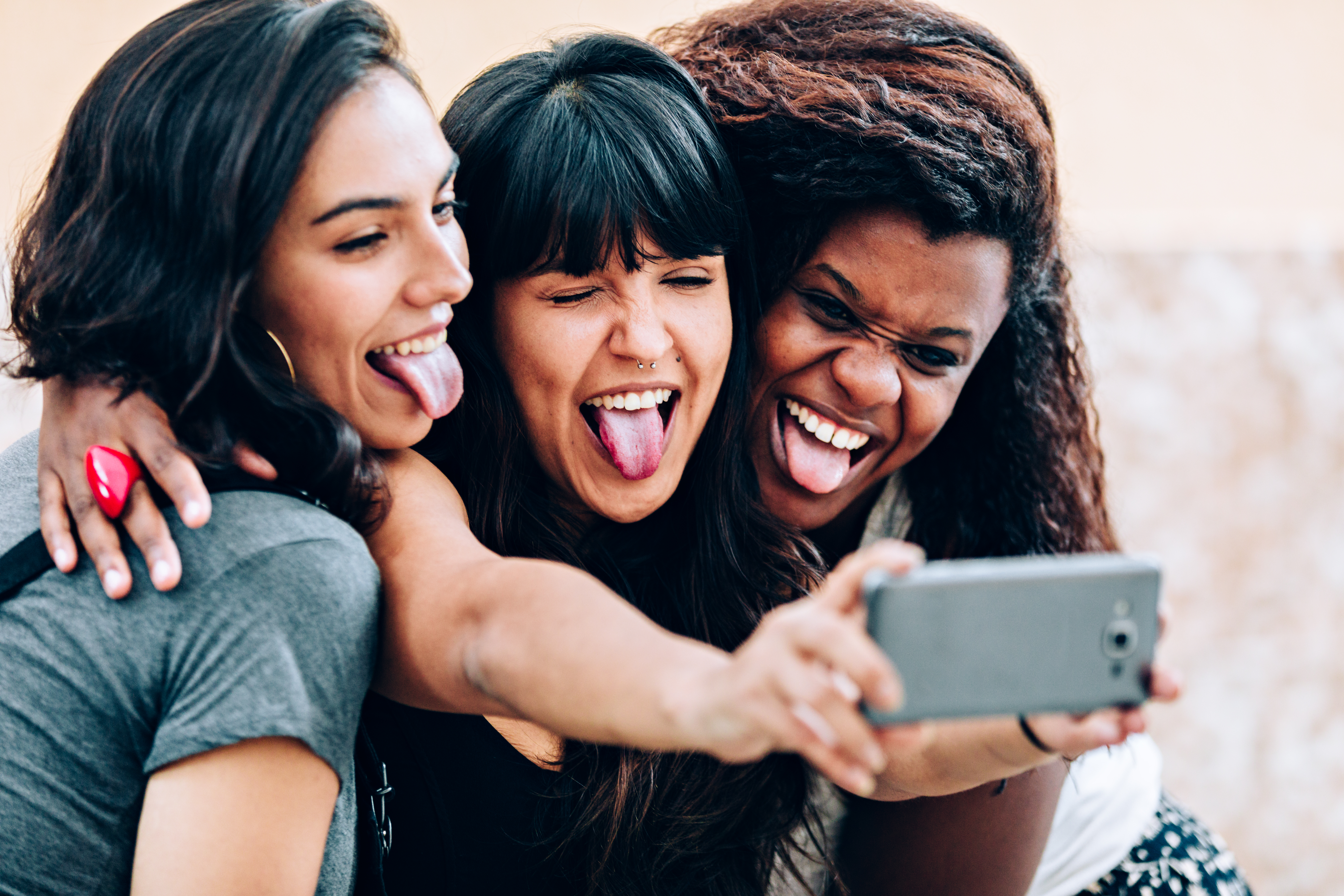 Three girl friends making funny faces for a selfie with cell phone
