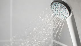 Close-Up Of Shower Head Spraying Water In Bathroom