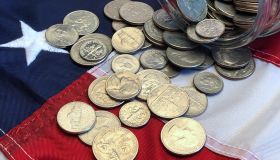 American quarters, nickels and dimes spilling from a jar onto an American flag