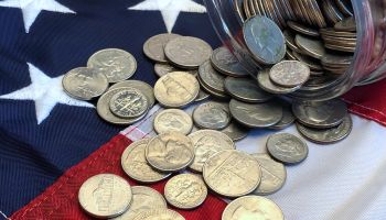 American quarters, nickels and dimes spilling from a jar onto an American flag