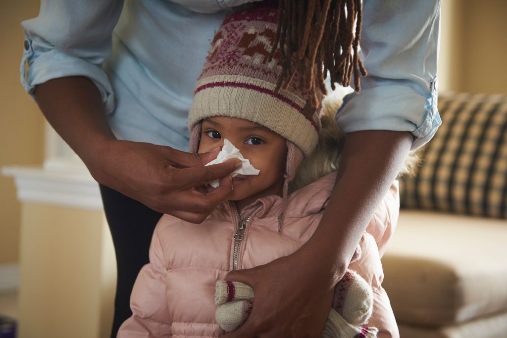 Mother blowing young daughter's nose