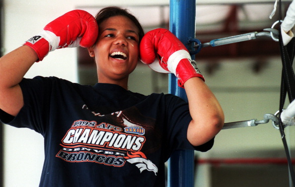 Boxer Freeda Foreman, daughter of former heaveyweight champion George Foreman, jokes with her trainer while posing for a portrait at America Presents Gym in Denver.