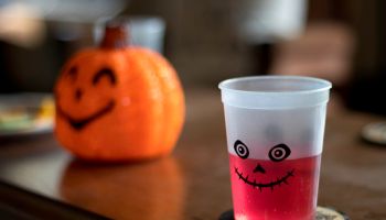 Red Halloween drink in cup on table with pumpkin