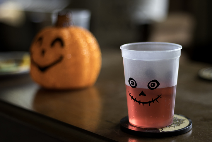 Red Halloween drink in cup on table with pumpkin