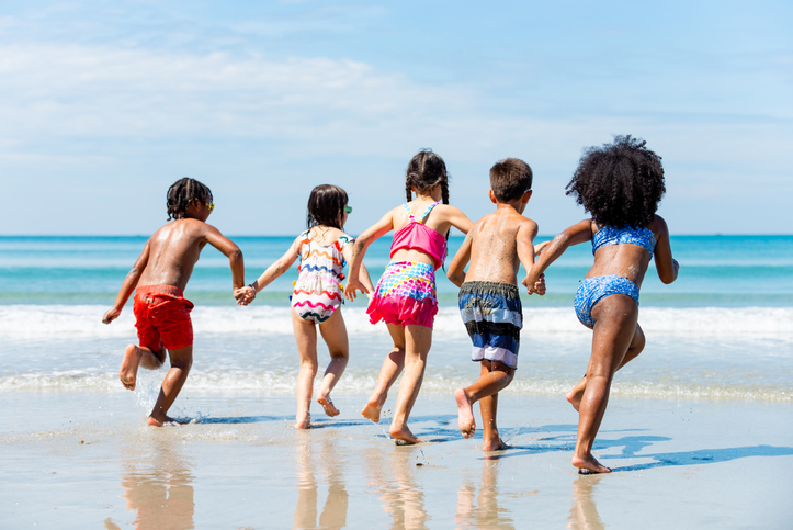 Group of Diversity children playing on tropical beach together on summer vacation at the sea.