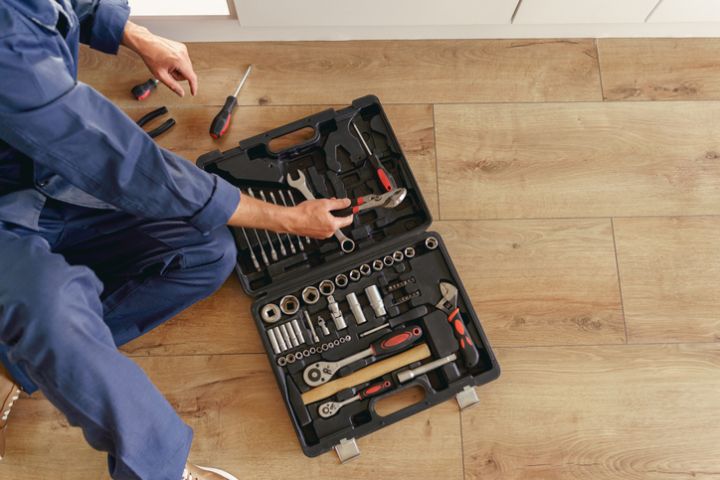 Top view of professional handyman with open tool bag sitting on home kitchen floor