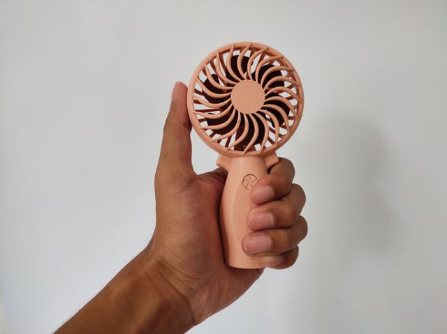 Hand holding small fan in summer