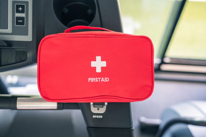 First aid kit red box in the fitness gym opposite the sport equipment and jogging simulators. Healthy lifestyle, safety and help concept
