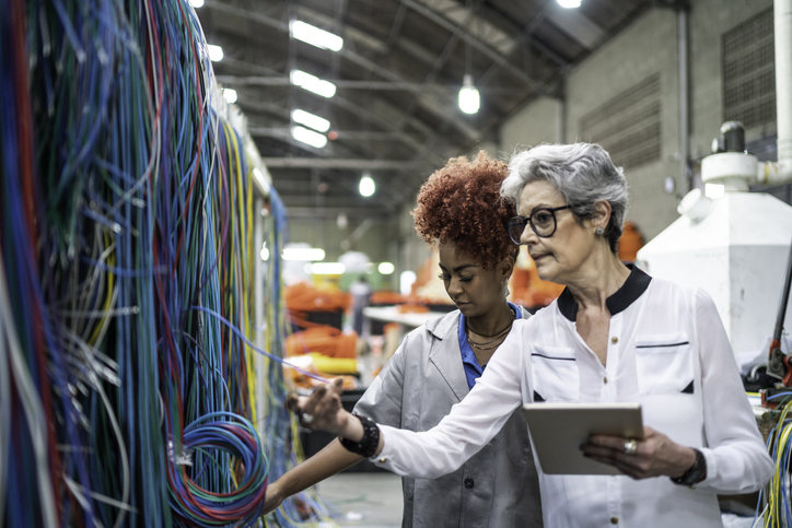 Manager using his tablet explaining her employee at industry