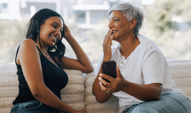 Couch Conversations Between Diverse Women Sharing Moments Indoors With Smartphone