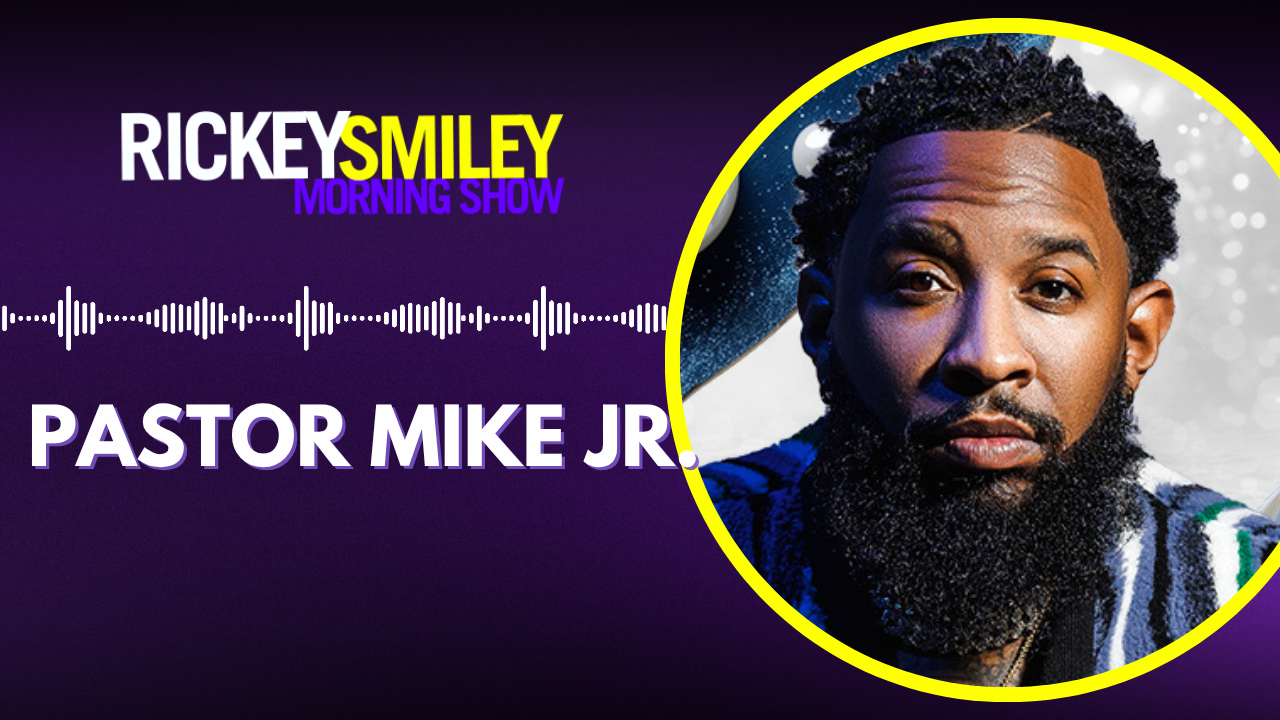 Portrait of a bearded Black man with curly hair wearing a blue jacket against a dark background, with text "RICKEY SMILEY MORNING SHOW" and "PASTOR MIKE JR.